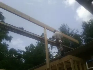 Carpenter setting a ridge beam over a new addition frame — Ice Dam Removal by Roofing Brothers in Napoleonville