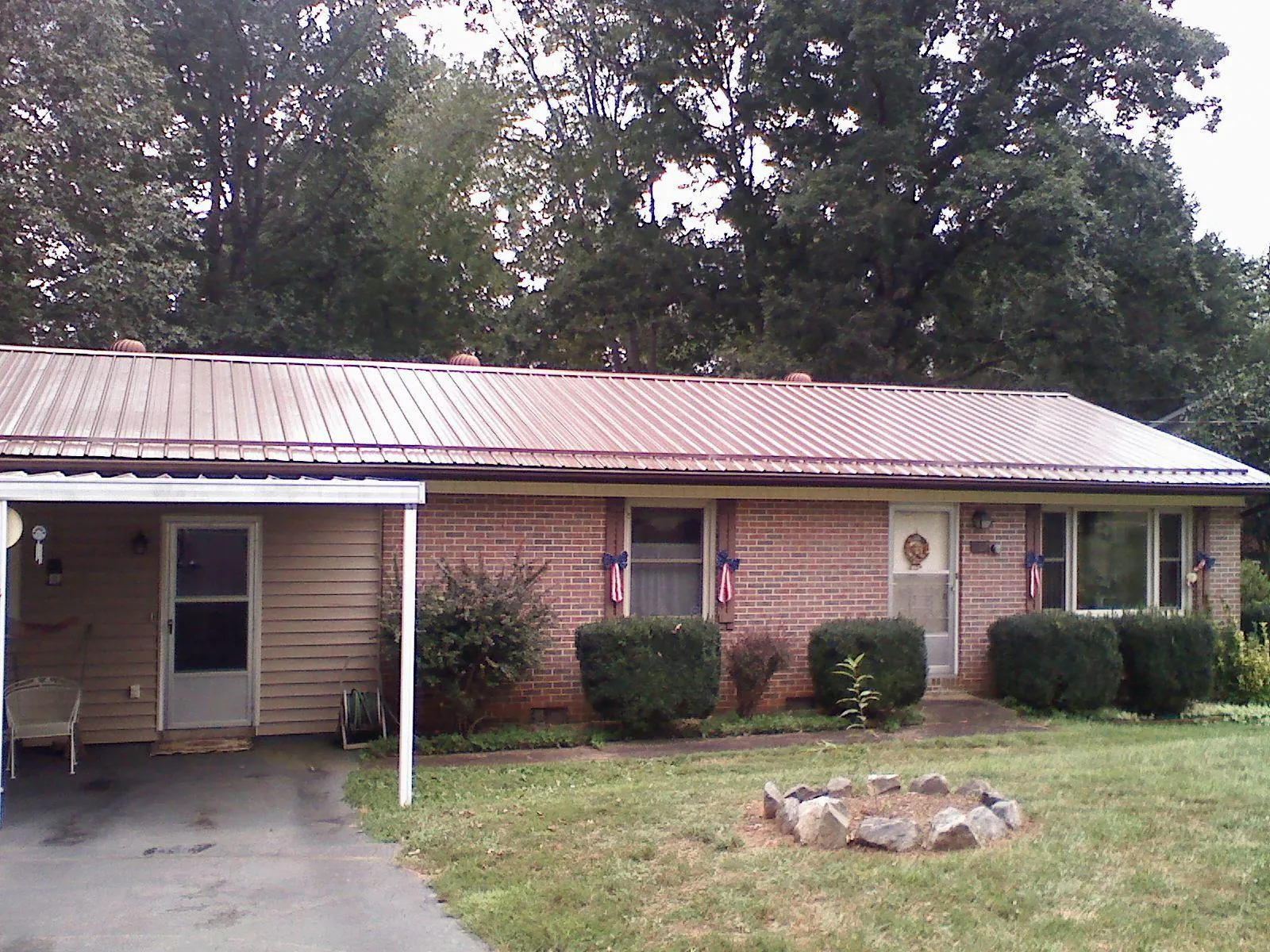 Bronze metal roof and carport on a brick ranch home — Roof Repair work by our crew in Napoleonville