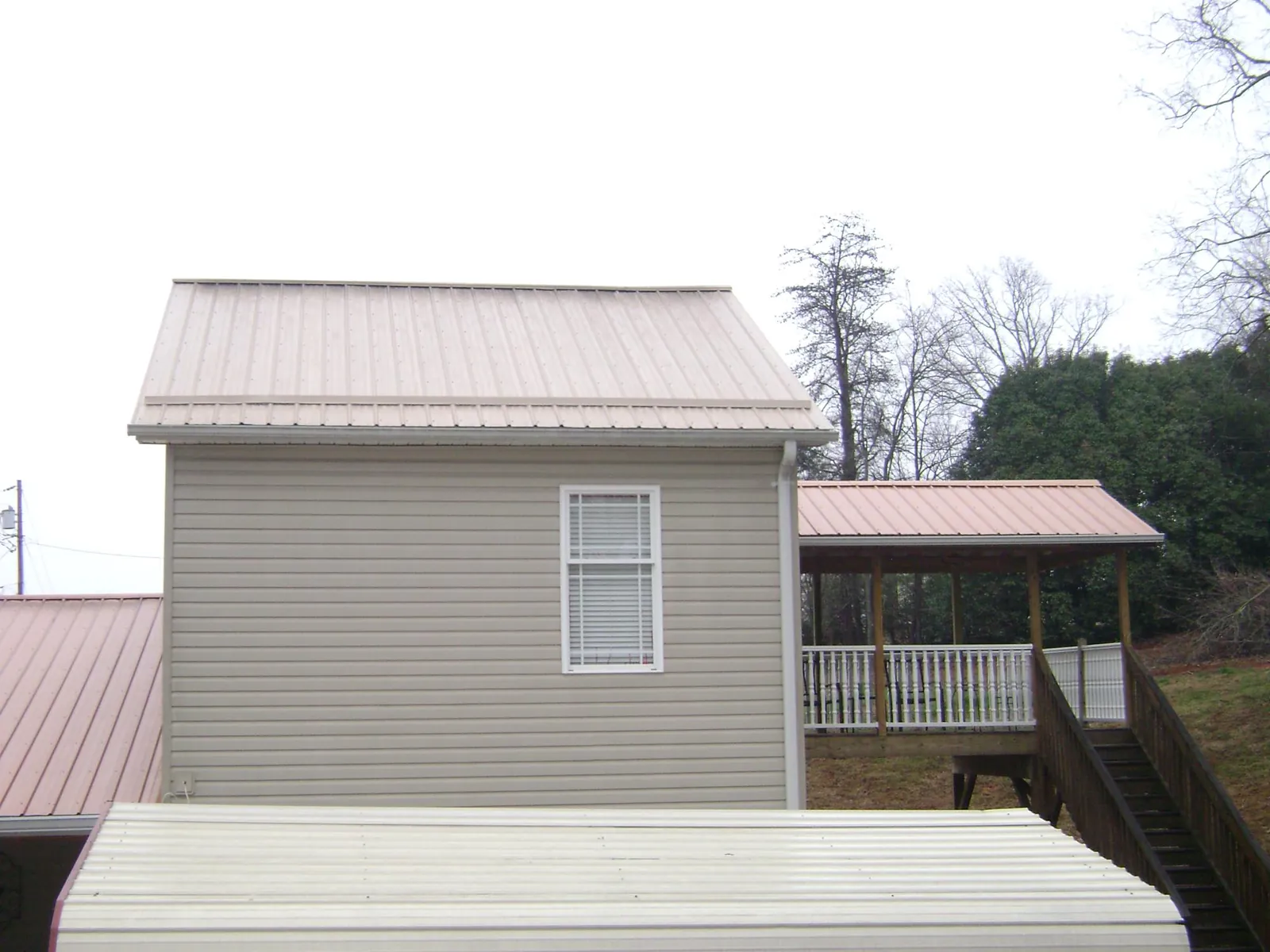 Tan metal roofs on a two story addition and attached porch, from a Roof Replacement job in Napoleonville