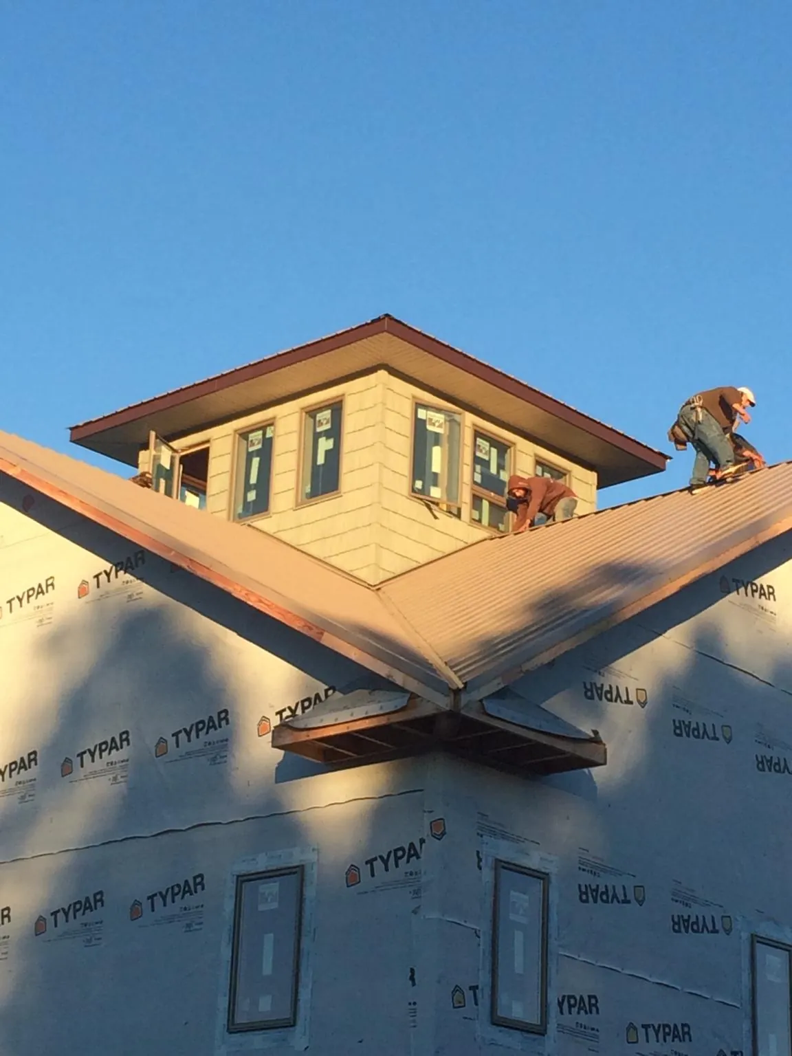 Roofers working around a rooftop cupola on a new metal roof at sunset — Roof Waterproofing in Napoleonville by Roofing Brothers